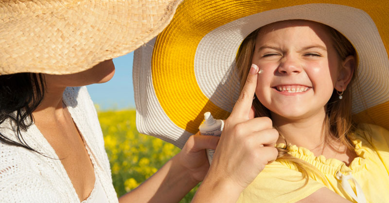Woman applying sunscreen to face of child